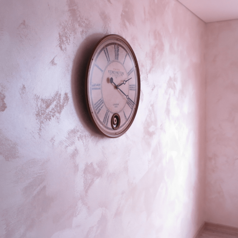 Beige Wand gestrichen mit einer Kreativtechnik und einer großen runden Uhr an der Wand