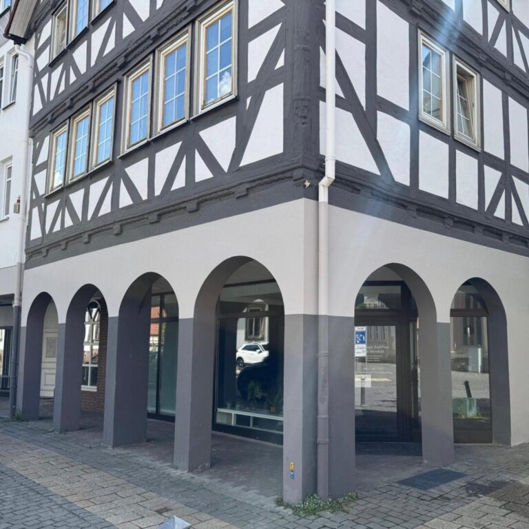 Fachwerkhaus-Fassade gestrichen in weiß-anthrazit. Eine Bogenstruktur mit Pfeilern.