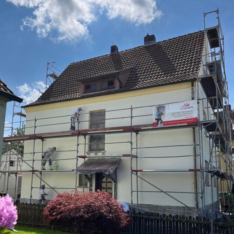 Hausfassade gestrichen in Weiß mit Gerüst vor dem haus