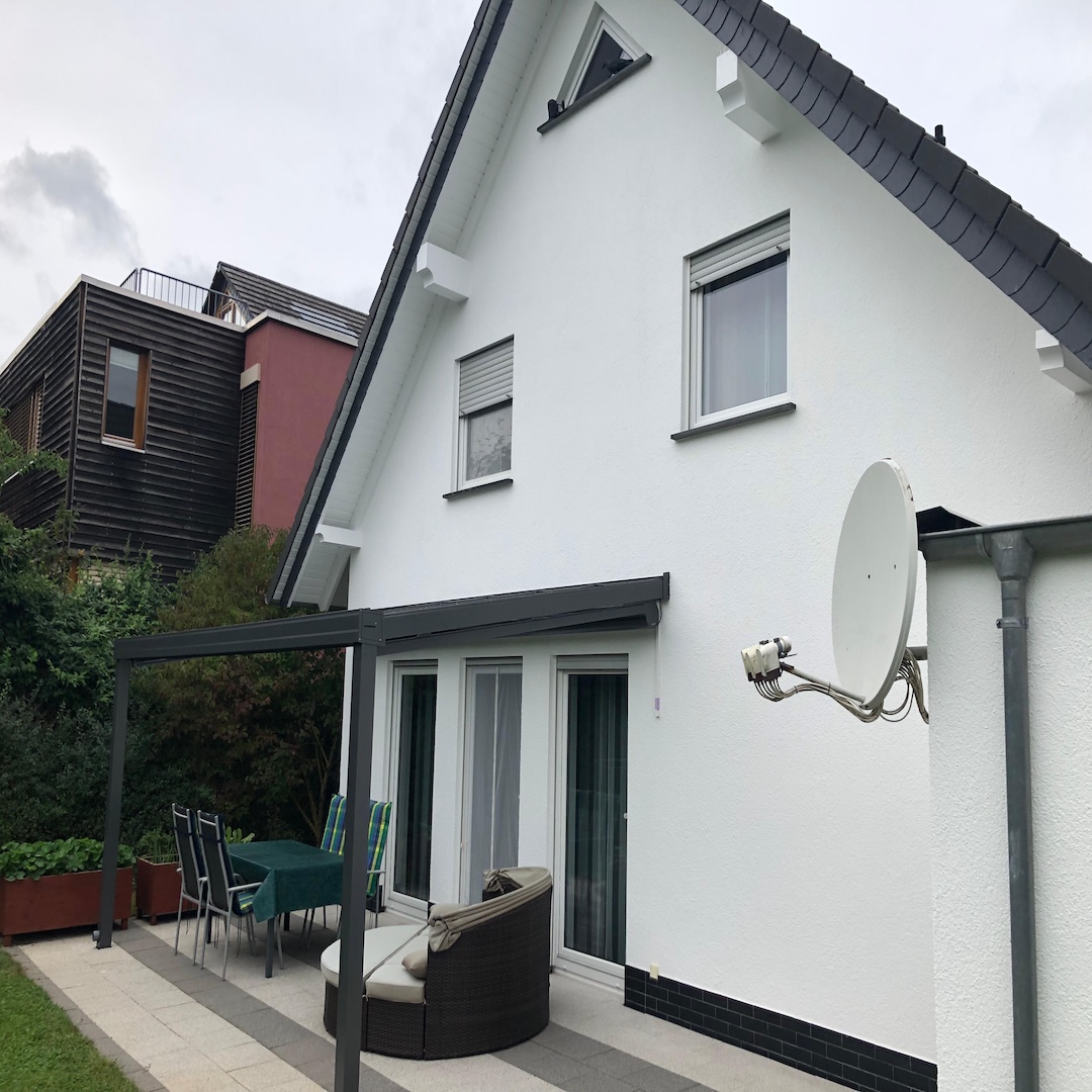 Hausfassade gestrichen in weiß mit Gartenlounge - nah